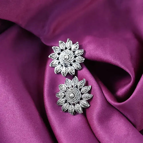 Silver floral earrings on a purple fabric background