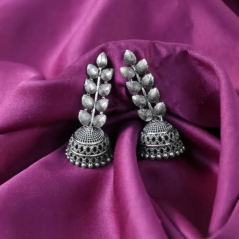 Silver earrings on a purple fabric background