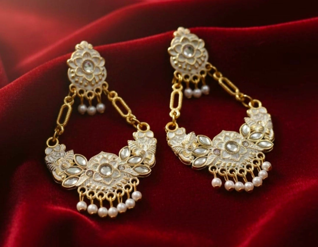 Ornate gold and pearl earrings on a red fabric background