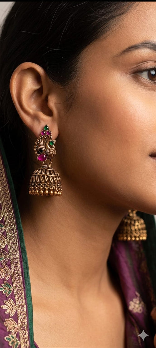 Antique gold jhumka earrings with green and pink enamel, long bell drop on ear
