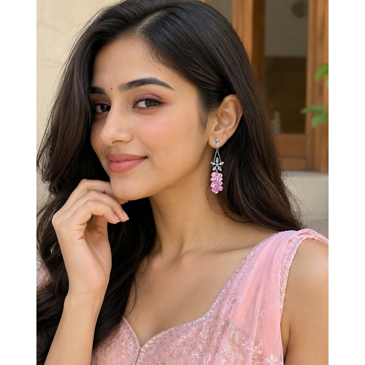 Pink crystal floral drop earrings worn by a woman, with