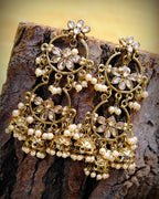 Close-up of gold chandbali earrings with white pearl strands, filigree and flower motifs