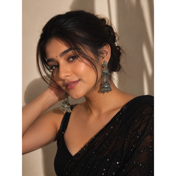 Silver-tone oxidised jhumka earrings with long chandelier bell shape on model