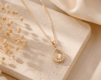 Rose gold chain necklace with teardrop crystal pendant, circular gem center and bezel.
