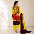 A woman stands with her back to the camera wearing a bright yellow traditional outfit with red and dark purple floral embroidery, matching yellow pants, and holding a yellow dupatta with a dark purple border.
